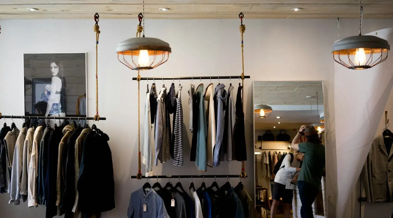 Interior of a clothing boutique with garments on rails under pendant lamps