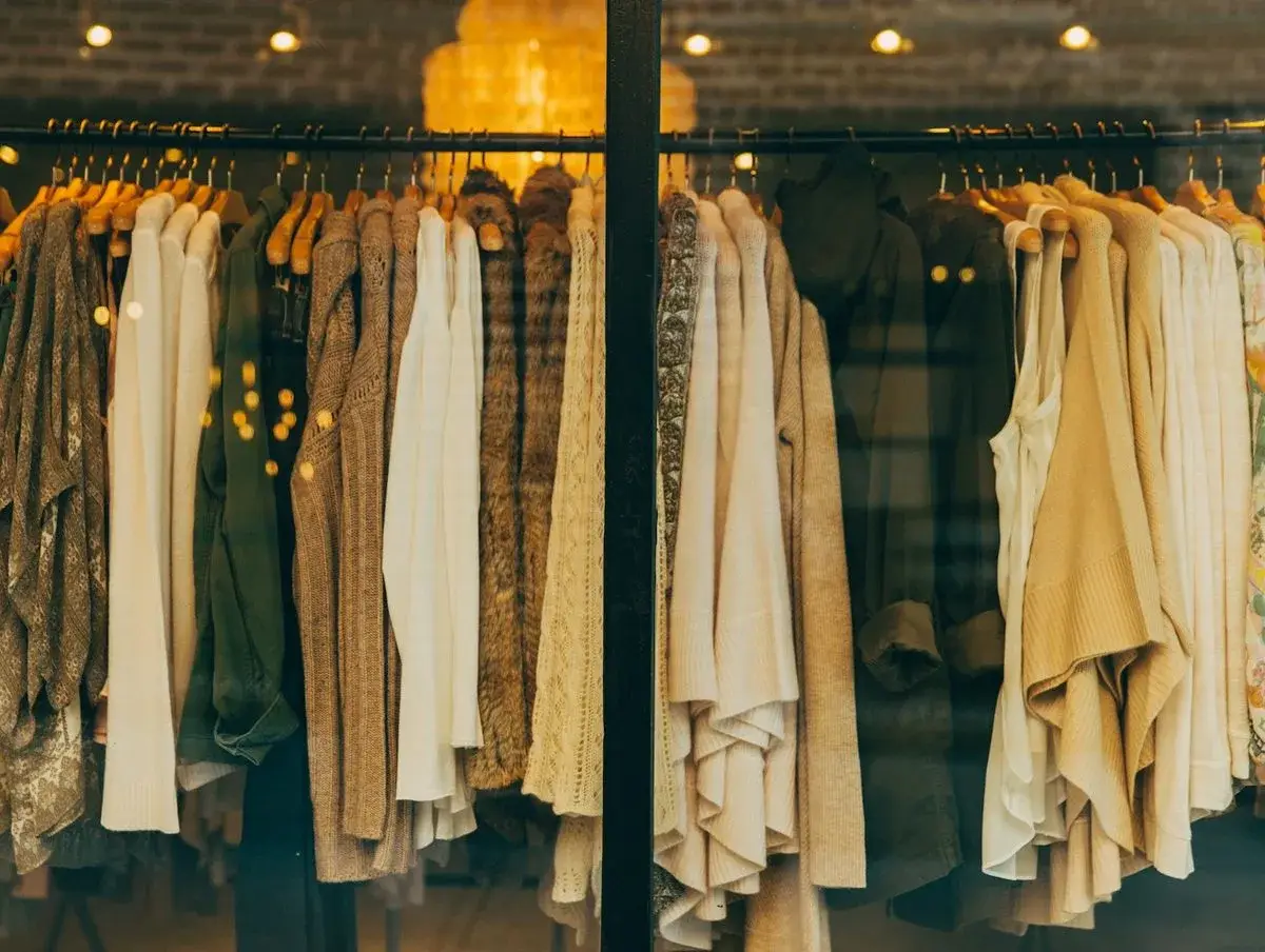 Warm-toned jackets and dresses hanging on racks in a clothing shop